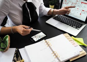A business professional working on real estate project plans using multiple devices in an office setting.