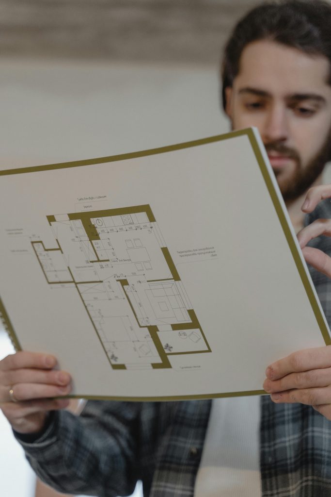 A man examines a detailed floor plan for a construction project indoors.