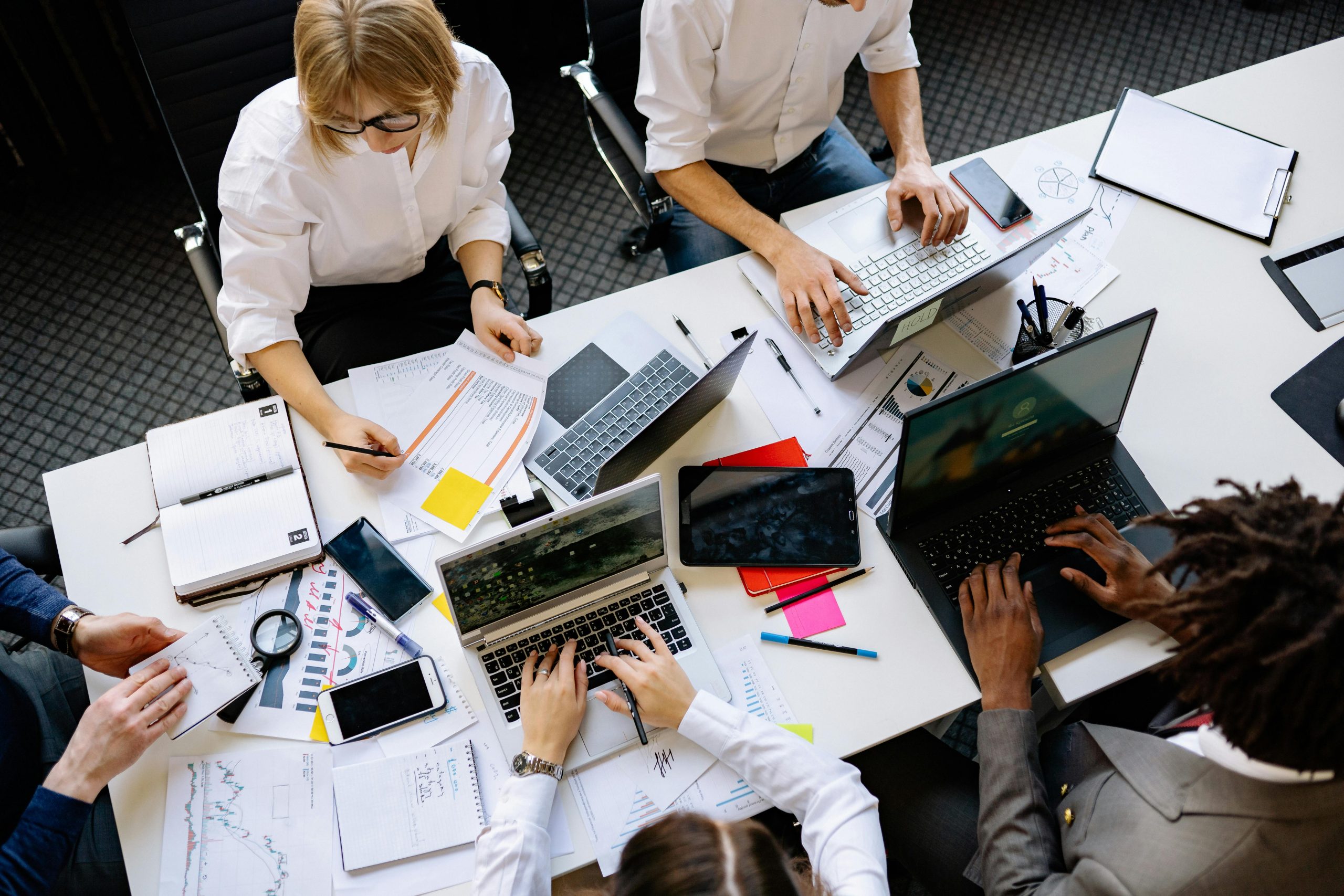 Vibrant office teamwork scene with laptops, documents, and diverse professionals in a meeting.