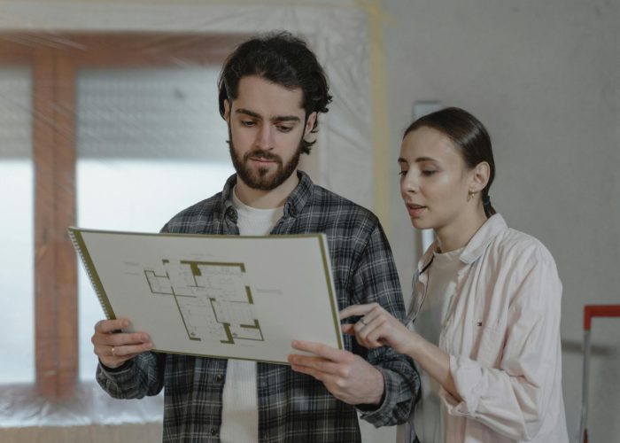 A man and woman examining a floor plan for home improvement indoors.