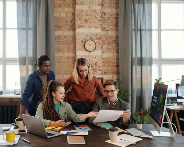 A diverse team of young professionals working on a business strategy in an urban office setting.
